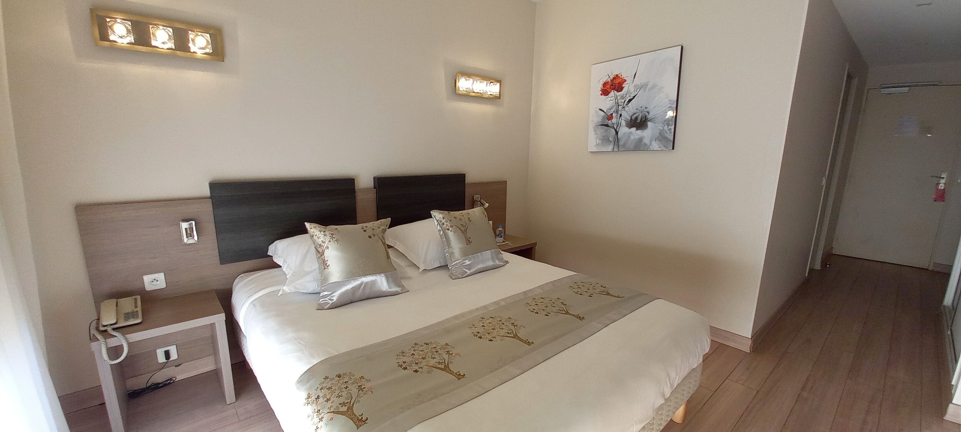 A neatly made bed with a floral bedspread, bedside lamps, and a telephone on a nightstand.
