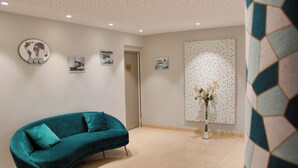 Un sofá color turquesa en una habitación con suelo de baldosas, un globo terráqueo sujeto a la pared y un cuadro enmarcado.