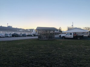 A parking lot with several cars, a small wooden structure, and a white school bus.