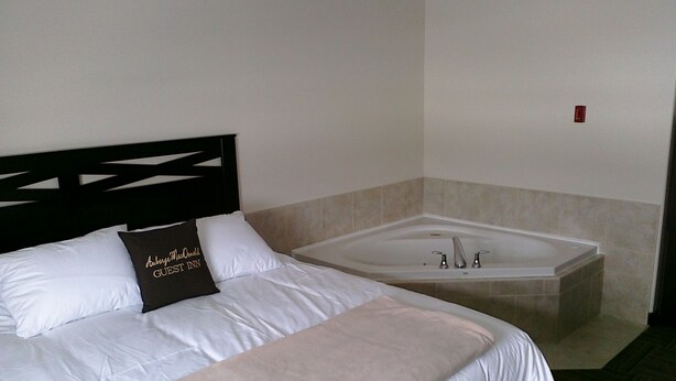 Une chambre d’hôtel avec un lit, une grande baignoire et une tête de lit.