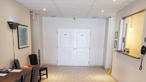 Une salle de conférence avec une longue table, des chaises, une porte blanche et un espace d’accueil avec un téléphone.