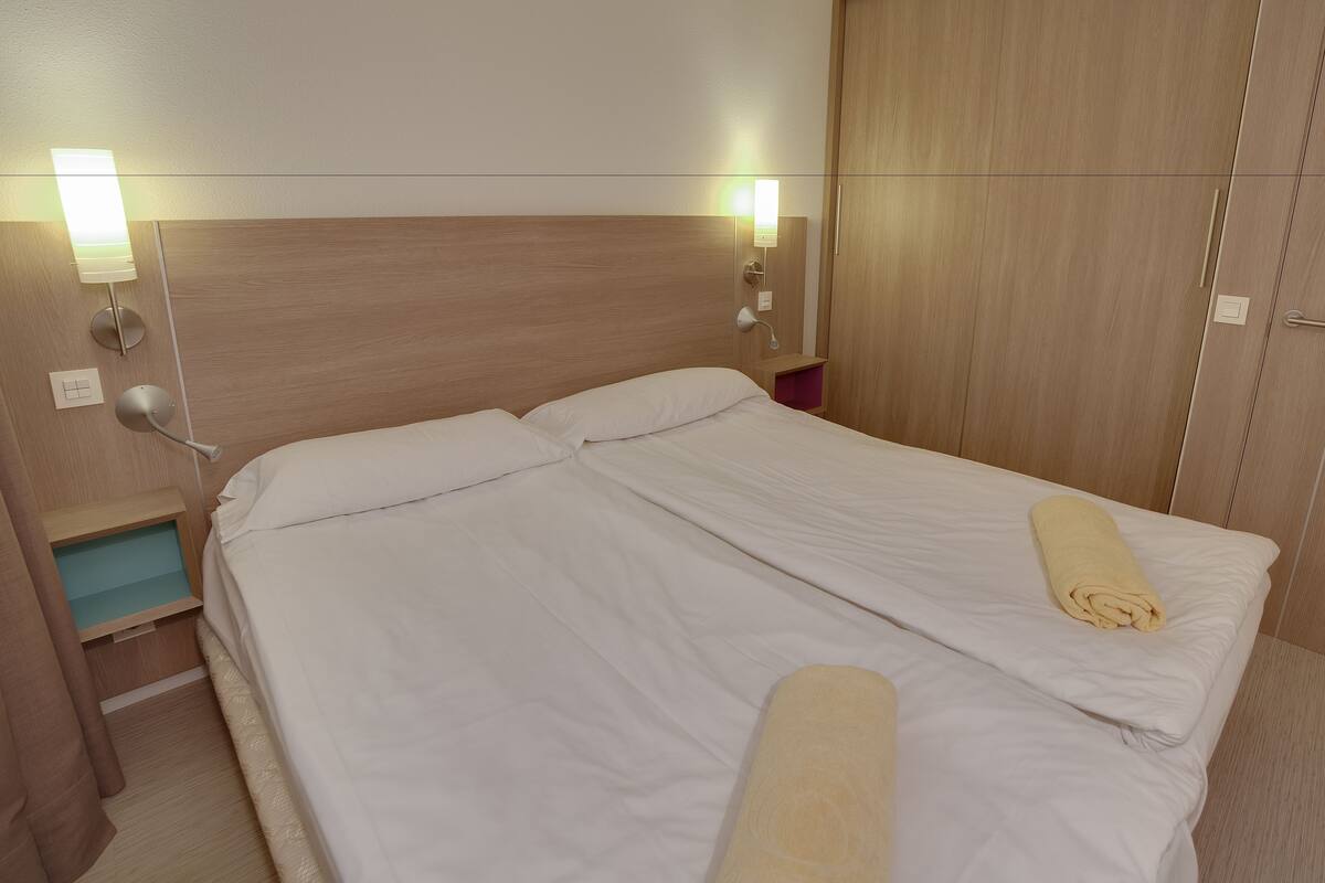 Hotellihuone, jossa on suuri sänky, yöpöydät ja vaatekaappi.