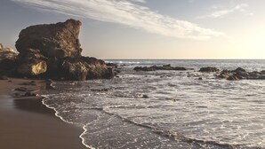 Une plage avec des formations rocheuses et des vagues.