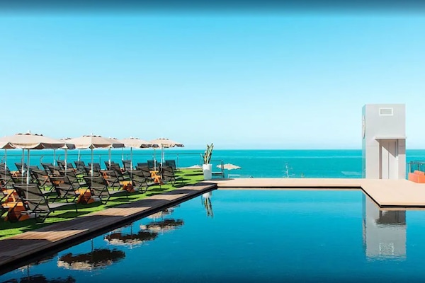 Una piscina al aire libre, sombrillas, sillones reclinables de piscina