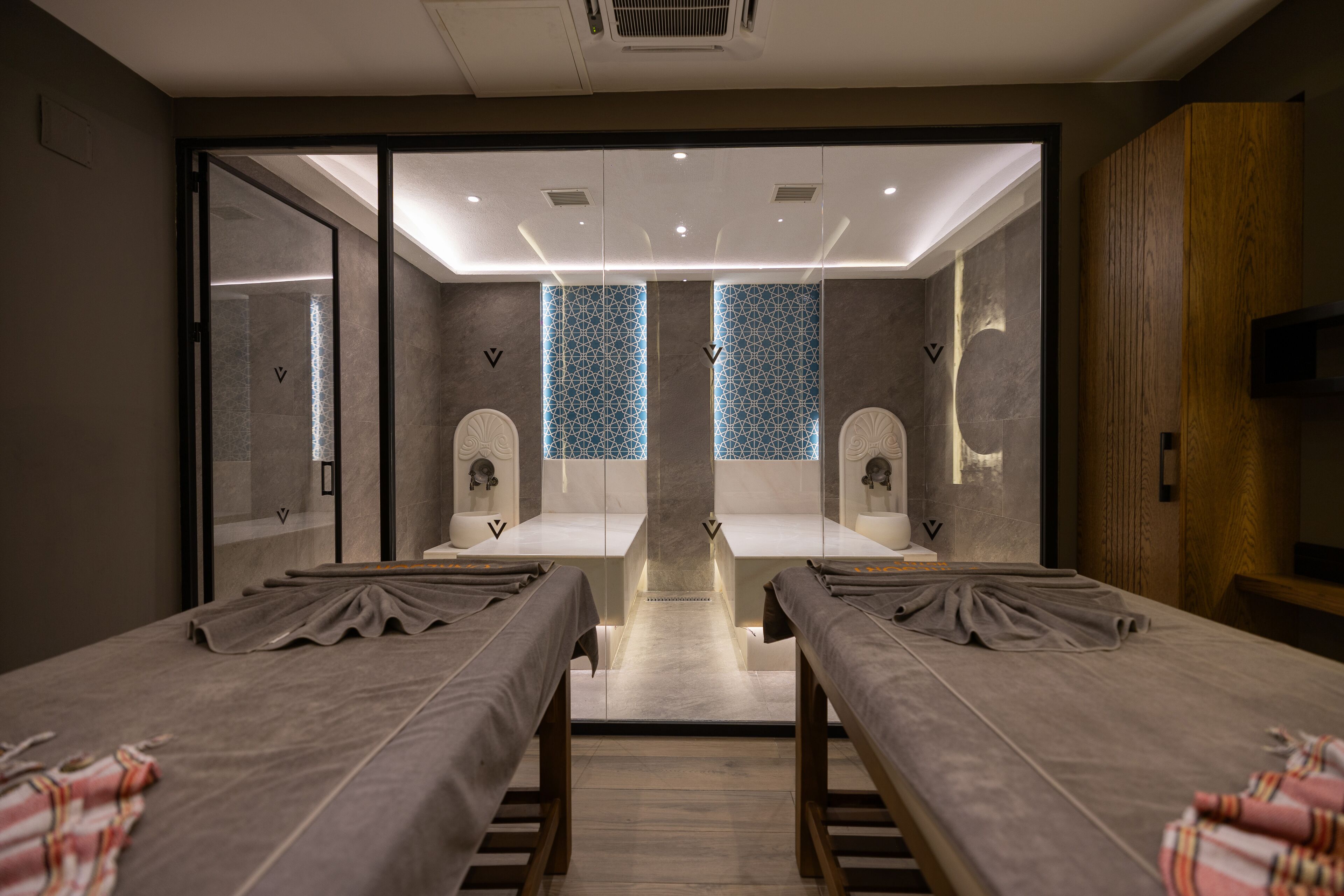 A modern hotel room with two beds, a shower area, and a television.