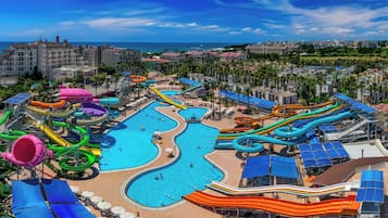 A water park with multiple slides and pools, surrounded by buildings and a clear sky.