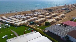 A beachside hotel with multiple rows of sunbeds and umbrellas, a large covered area, and a view of the sea. - Side Win Hotel (Manavgat)