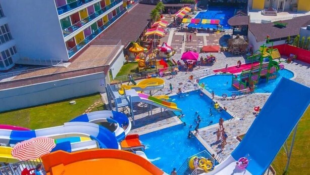 A water park with multiple slides and pools, surrounded by buildings with balconies. - Side Win Hotel (Manavgat)