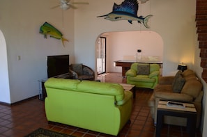 A living room with a green sofa, a brown sofa, a TV, and a ceiling fan.