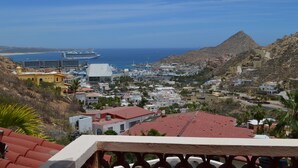 A coastal town with a prominent mountain, a cruise ship dock, and a mix of residential buildings. - Casa Rosa (Cabo San Lucas)