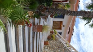 A stone staircase with white railings leading to a building with a blue door and a decorative wall. - Casa Rosa (Cabo San Lucas)