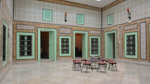 A spacious courtyard with tiled flooring, green doors, and patterned walls. - Dar Ya - Hostel (Tunis)