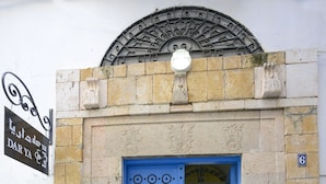 A blue door with decorative patterns, a sign above it, and a number '6' on the wall. - Dar Ya - Hostel (Tunis)