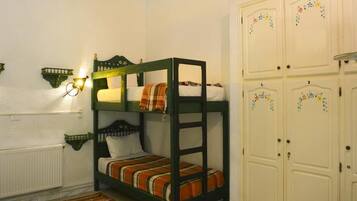 A bunk bed room with a radiator, a small table, and a cabinet.