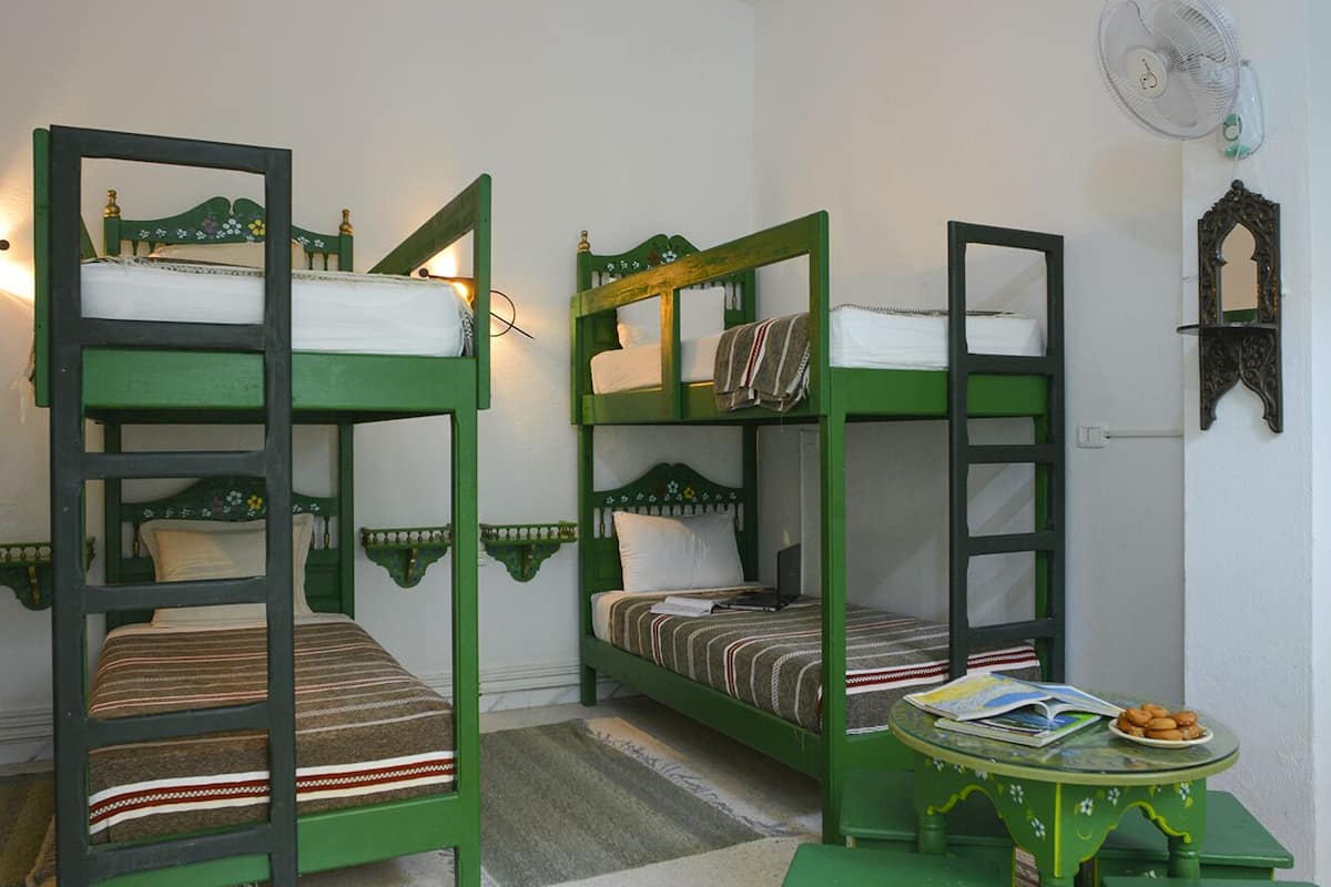 A room with bunk beds, a small table, and a mirror.