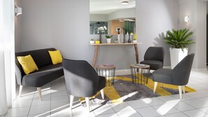 Una sala de estar moderna con un sofá gris, dos sillones, una mesa de centro y un espejo grande en la pared.