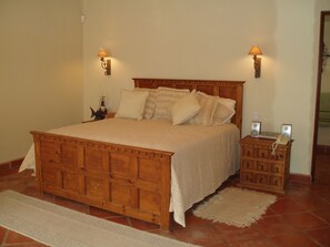 A wooden bed with a quilted bedspread, two wall-mounted lamps, a bedside table with a telephone, and a small wooden cabinet. - Cabo Vista (Cabo San Lucas)