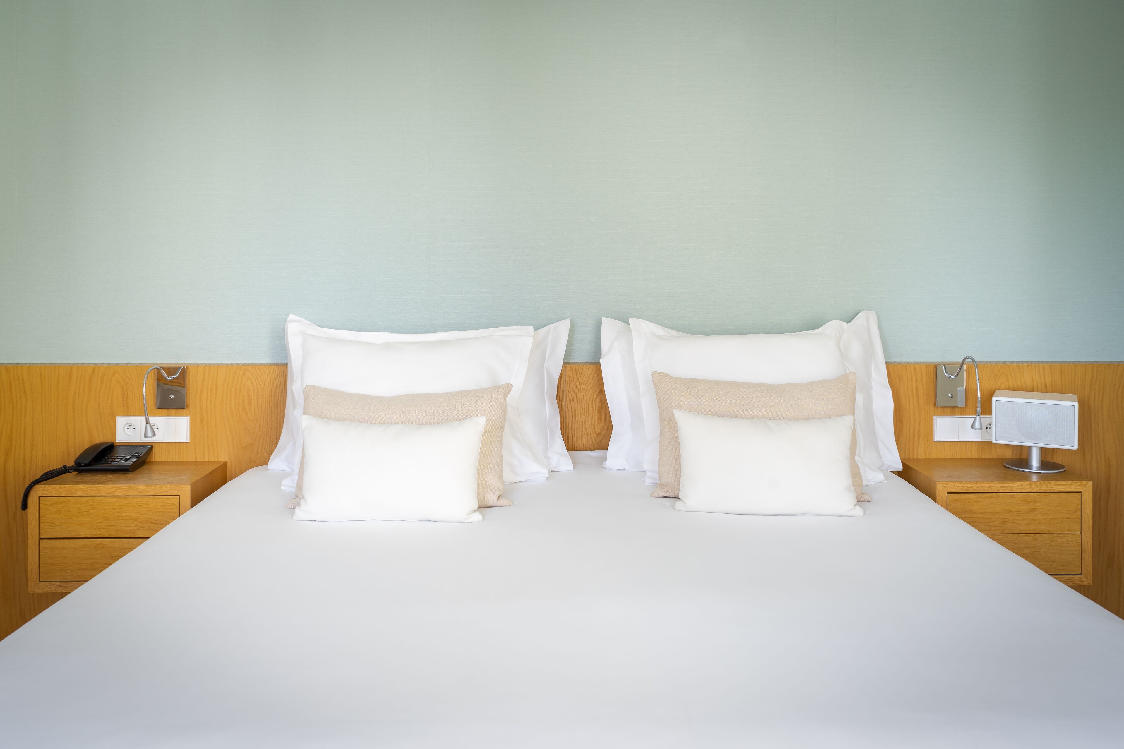 Une chambre d’hôtel avec un grand lit, deux tables de chevet, une commode, un téléphone et une lampe de chevet.