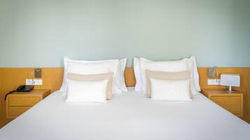 Une chambre d’hôtel avec un grand lit, deux tables de chevet, une commode, un téléphone et une lampe de chevet.