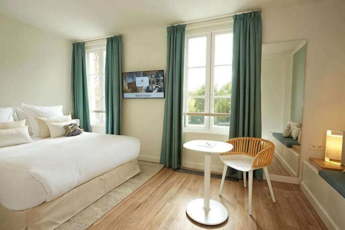 A hotel room with a bed, a TV, a small table, and a chair.