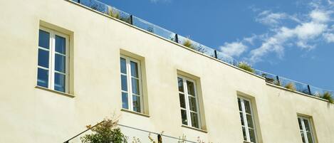 Un bâtiment doté de trois fenêtres et d’un balcon orné de plantes.