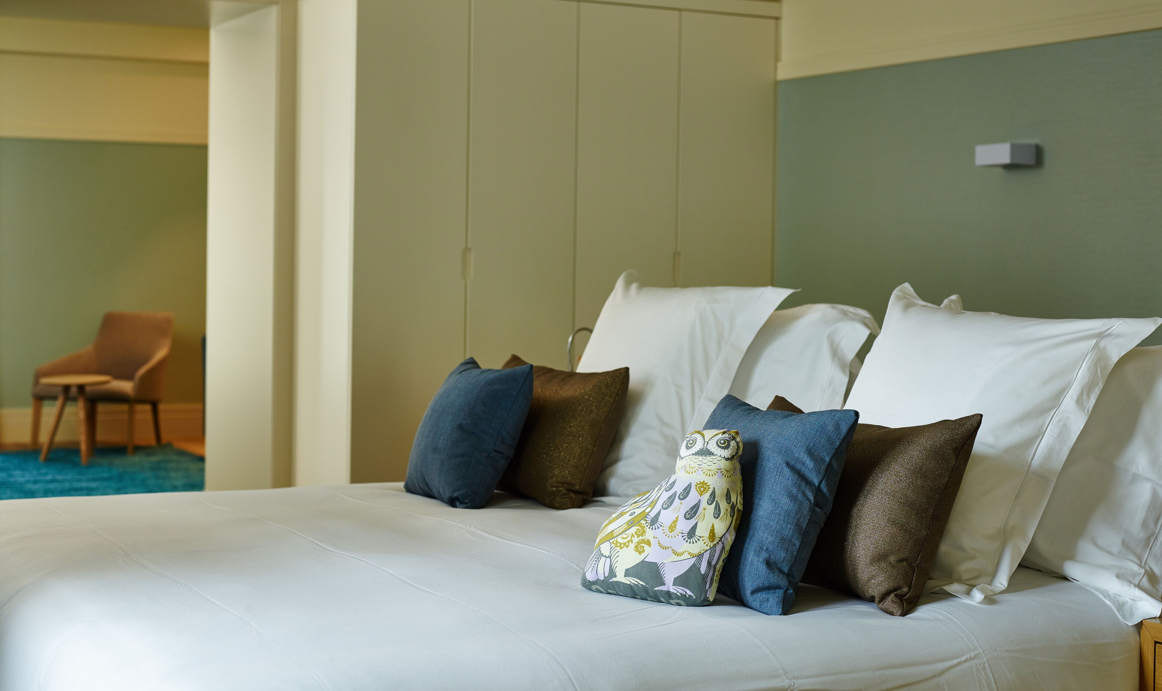 A neatly made bed with white linens and several decorative pillows.