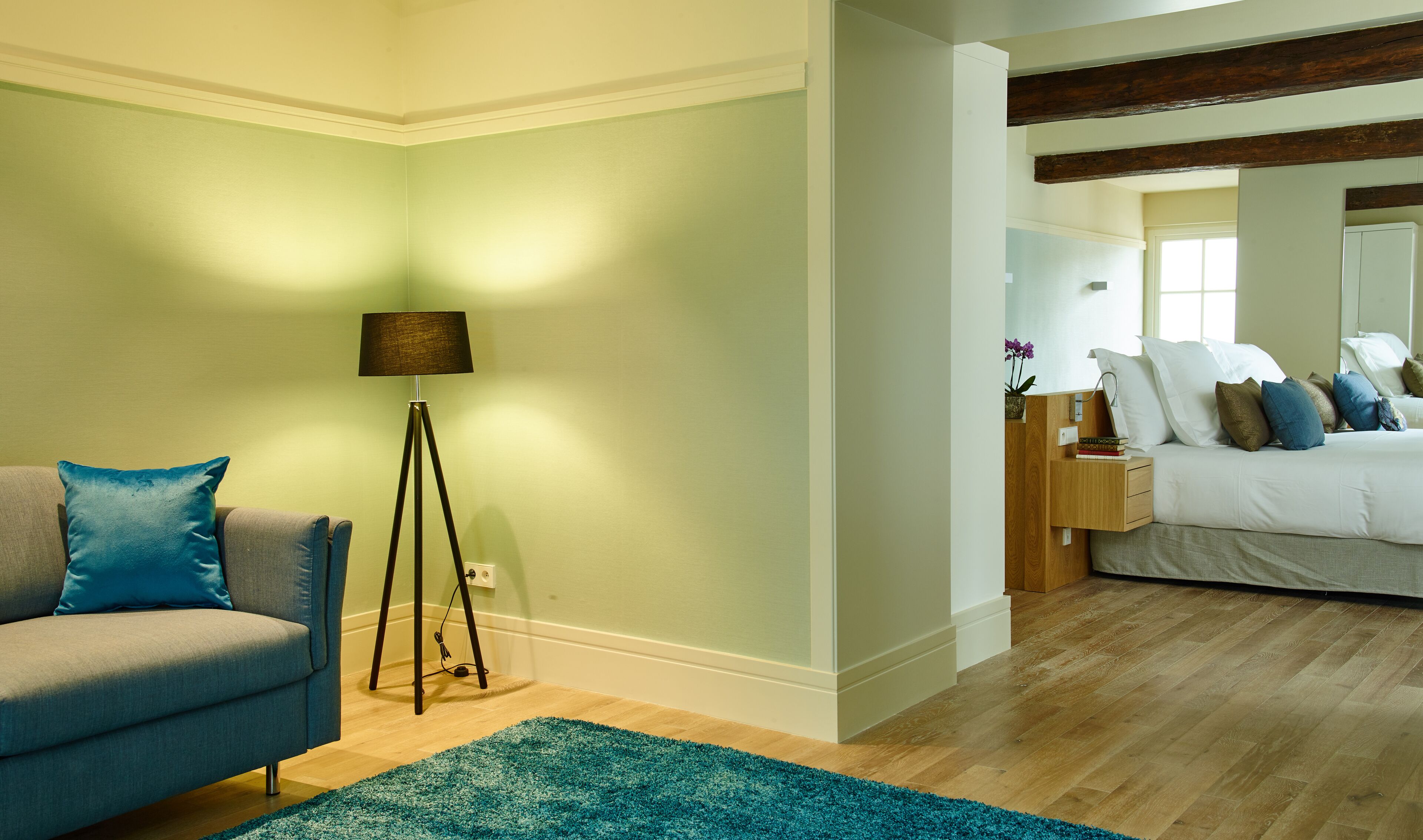 Une chambre à coucher avec un lit, une table de chevet, une lampe et un tapis bleu.