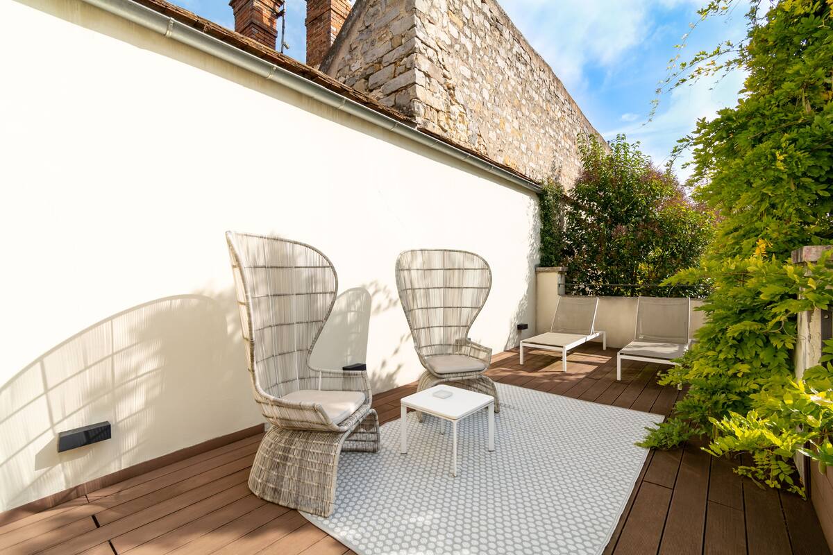 A patio with wicker chairs, a small table, and a patterned rug.