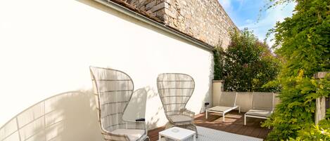 A patio with wicker chairs, a small table, and a patterned rug.