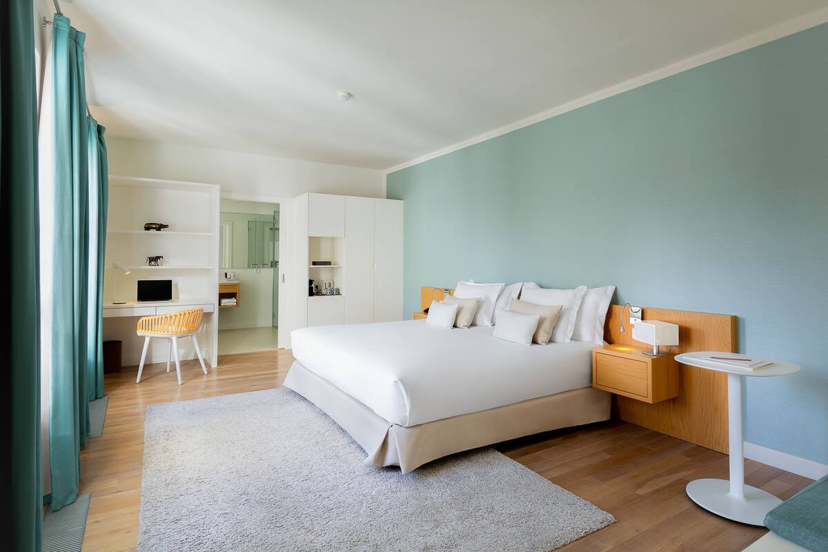 A modern bedroom with a large bed, bedside tables, a desk, and a chair.