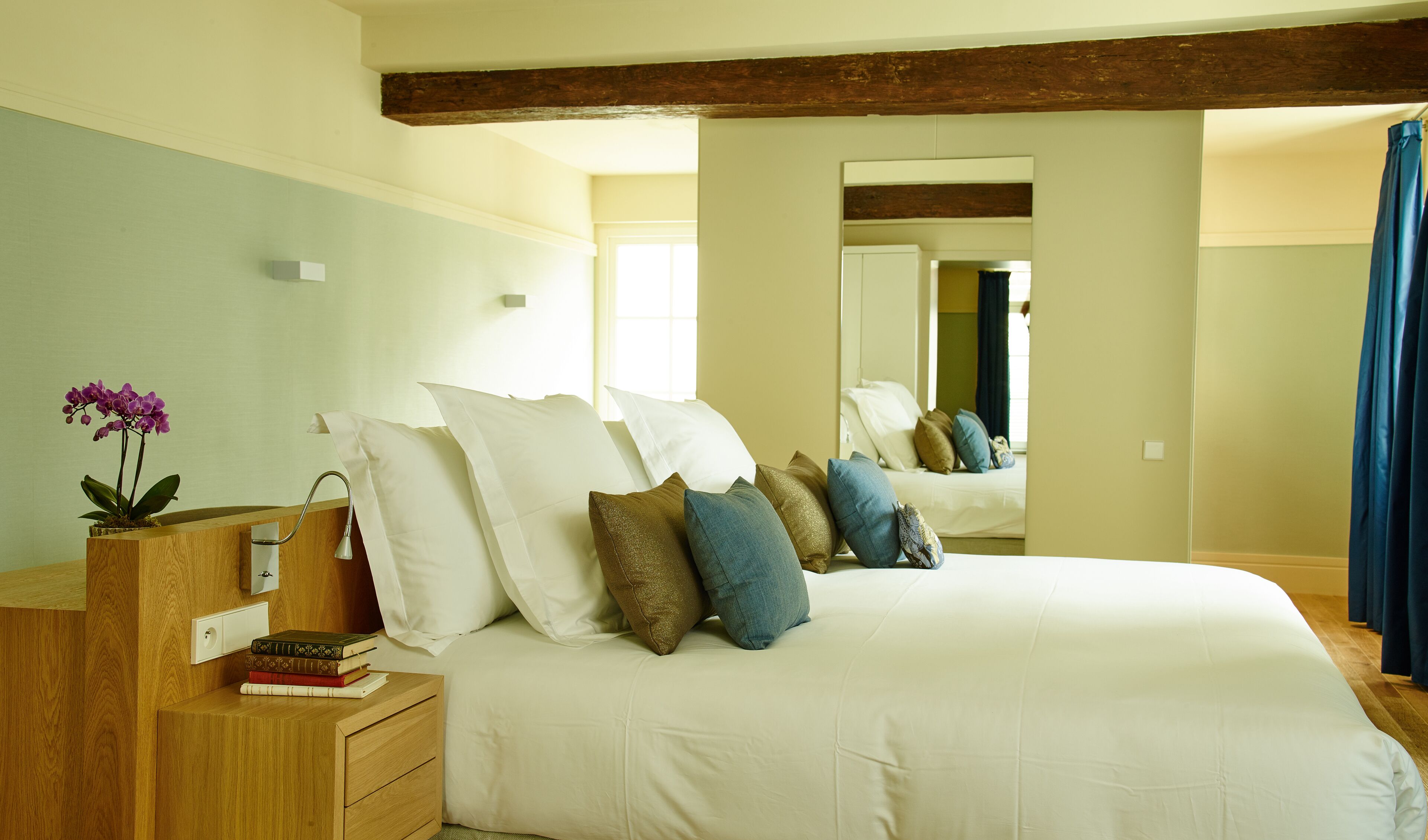 A bedroom with a large bed, wooden headboard, bedside tables, and a mirror.