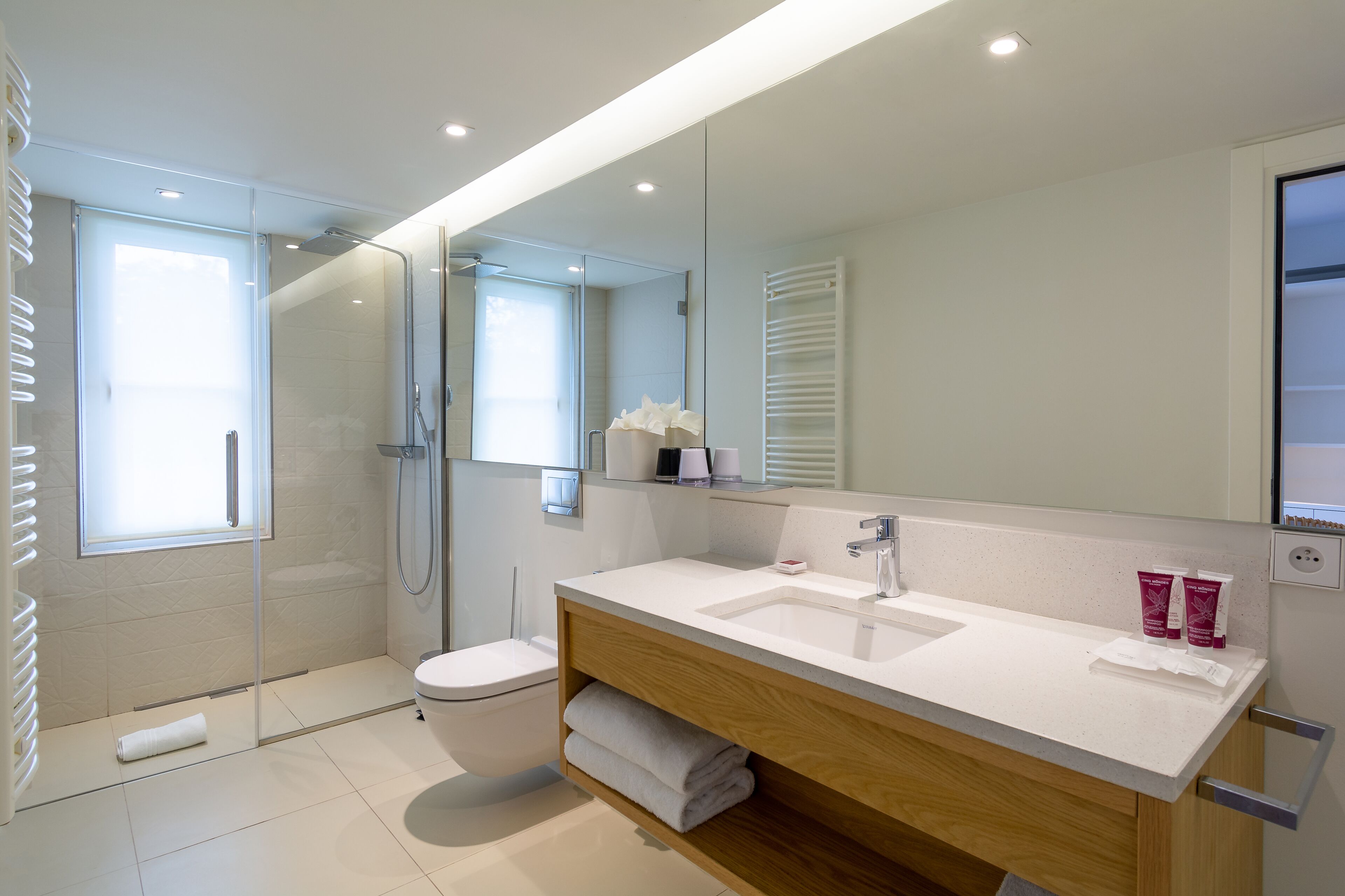 Een moderne badkamer met een douchecabine van glas, een wit wastafelmeubel en een grote spiegel.