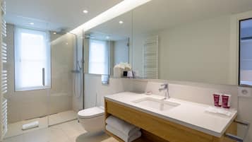 Een moderne badkamer met een douchecabine van glas, een wit wastafelmeubel en een grote spiegel.