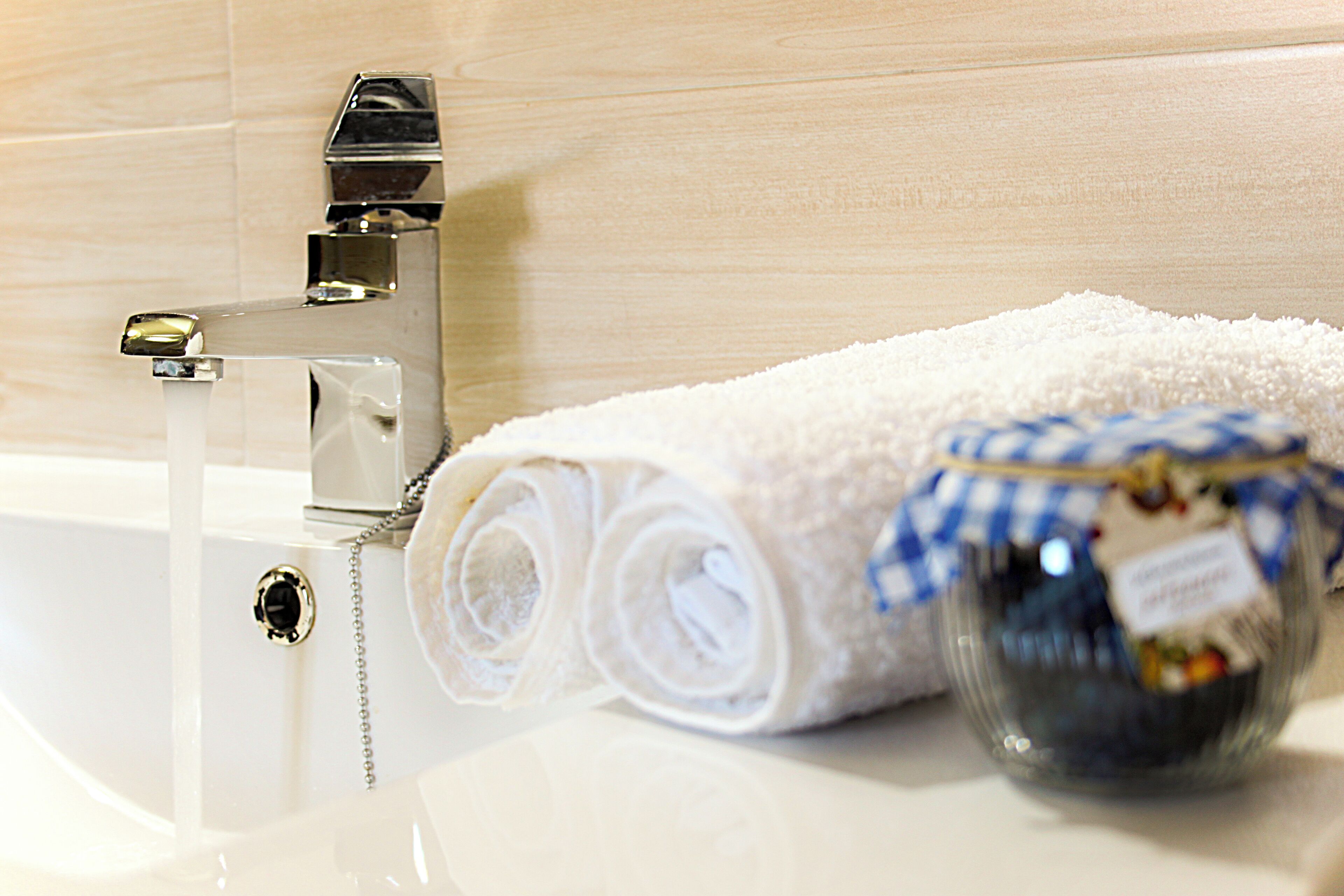 A bathroom with a white bathtub, a towel, and a glass jar with a label.