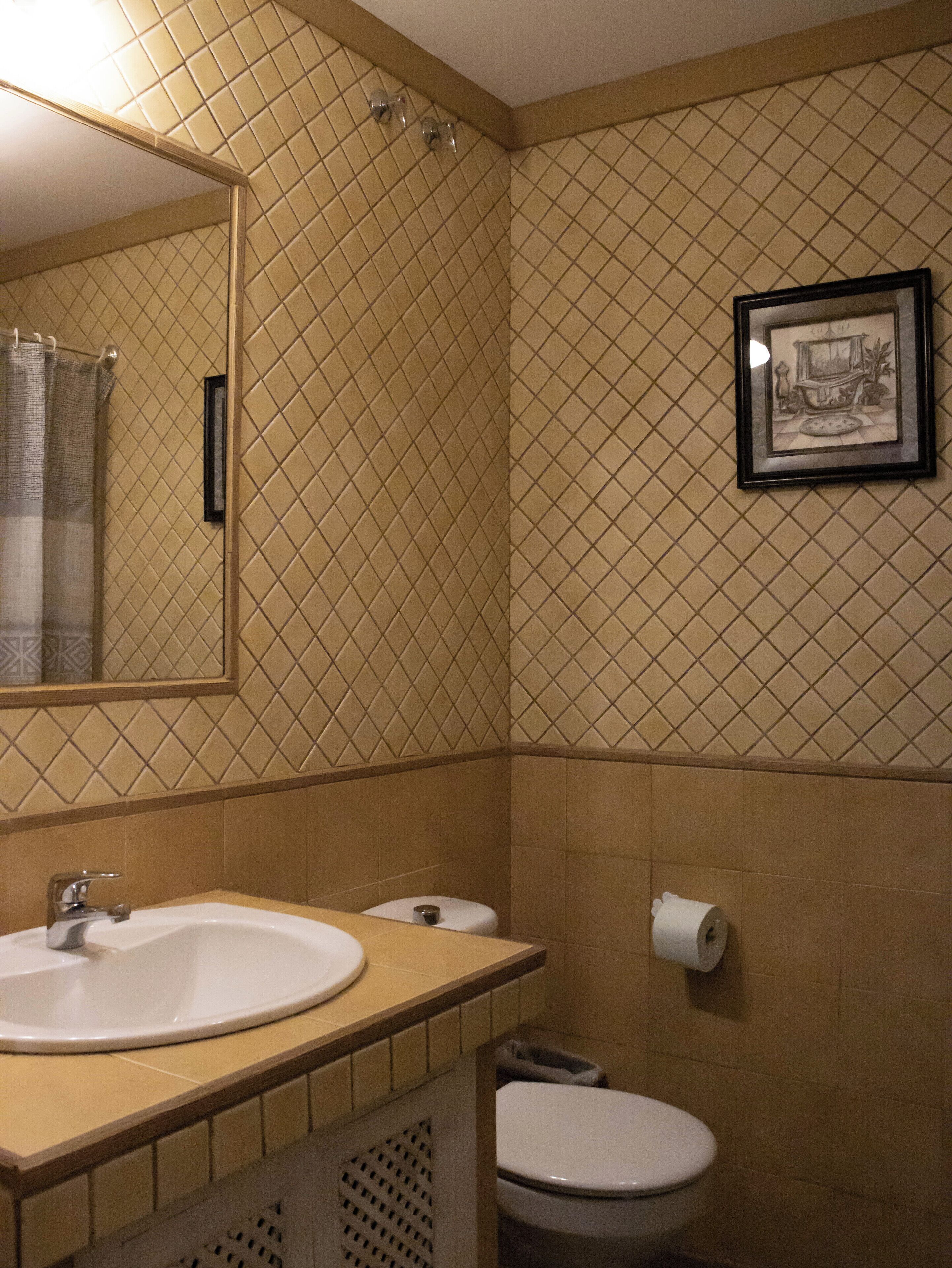 Un baño con lavamanos, inodoro y un cuadro en la pared.
