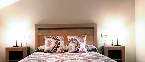 A bedroom with a large bed, two bedside tables, and a wooden headboard.