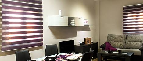 A modern living room with a dining area, featuring a sofa, a coffee table, and a TV.