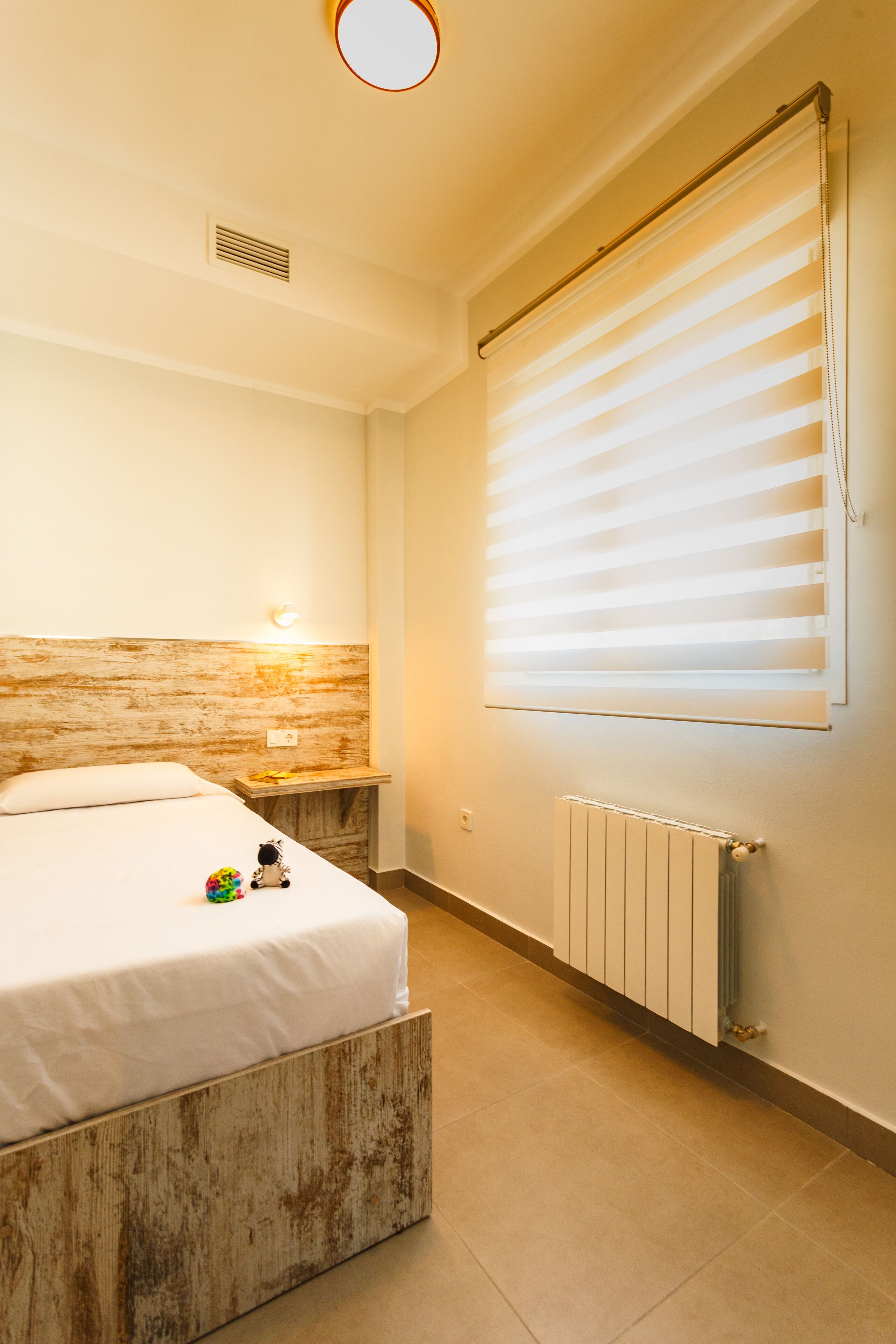Un dormitorio con cama, mesita de noche y radiador.