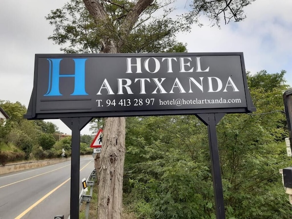 A sign for Hotel Artxanda with contact information and a pedestrian crossing sign nearby. - Hotel Artxanda (Bilbao)