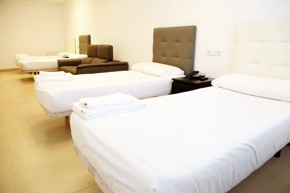 Quarto de hotel com duas camas de solteiro, um sofá e uma mesa de cabeceira com telefone.