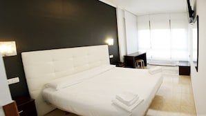 Una habitación de hotel moderna con una cama grande, un escritorio pequeño, una silla y un radiador.