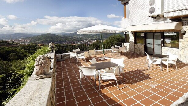 Una terraza con asientos al aire libre, un muro de piedra y vistas del paisaje.