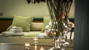 Una cama bien hecha con toallas dobladas, un jarrón con flores y velas sobre una mesa.