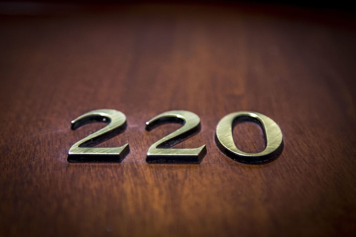 Three metallic numbers '2', '2', '0' on a wooden surface.