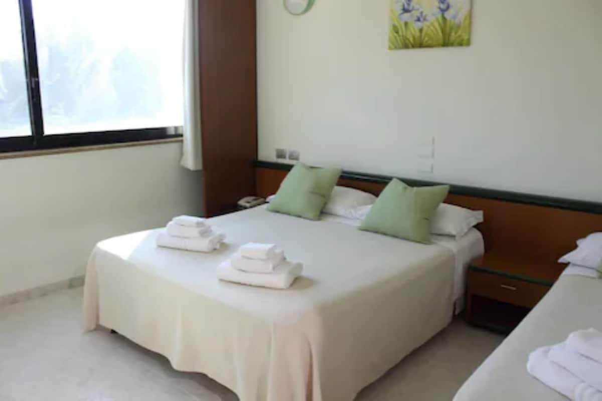 A hotel room with a large bed, two pillows, a nightstand, and a painting on the wall.
