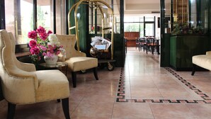 Un vestíbulo con dos sillones cómodos, una mesita con un jarrón de flores y un espejo decorativo.