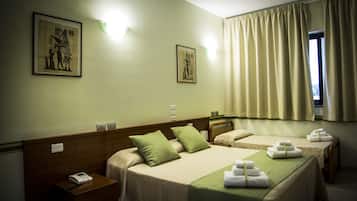 A hotel room with two beds, a bedside table with a phone, and a window with curtains.