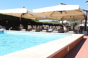 Una piscina con sillas de descanso y sombrillas.