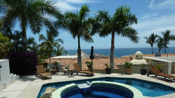 A pool area with lounge chairs, a hot tub, and a view of the ocean. - Casa Sun Guadalupe (San José del Cabo)