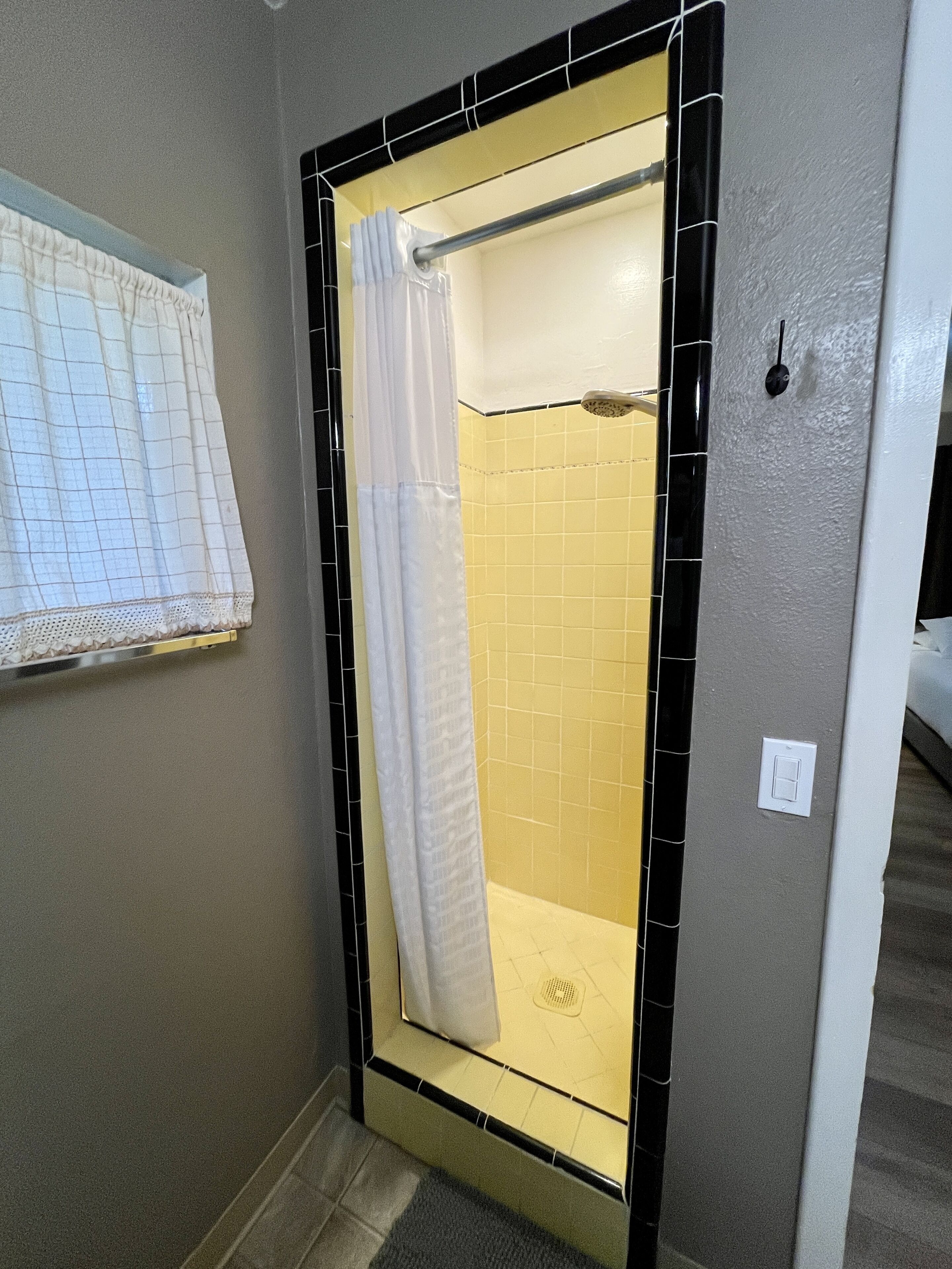 A bathroom with a shower, tiled walls, a towel rack, and a light switch.